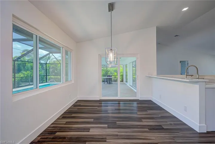 Unfurnished dining area featuring lofted ceiling, baseboards, dark wood-type flooring, and a chandelier