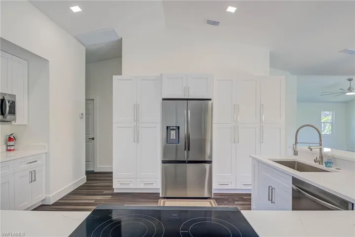 Kitchen featuring stainless steel appliances, a sink, white cabinets, and lofted ceiling