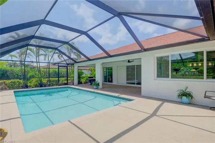Outdoor pool featuring a patio area, ceiling fan, and glass enclosure