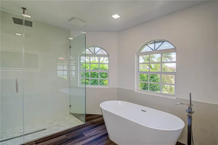 Full bathroom with a stall shower, a soaking tub, and wood finished floors