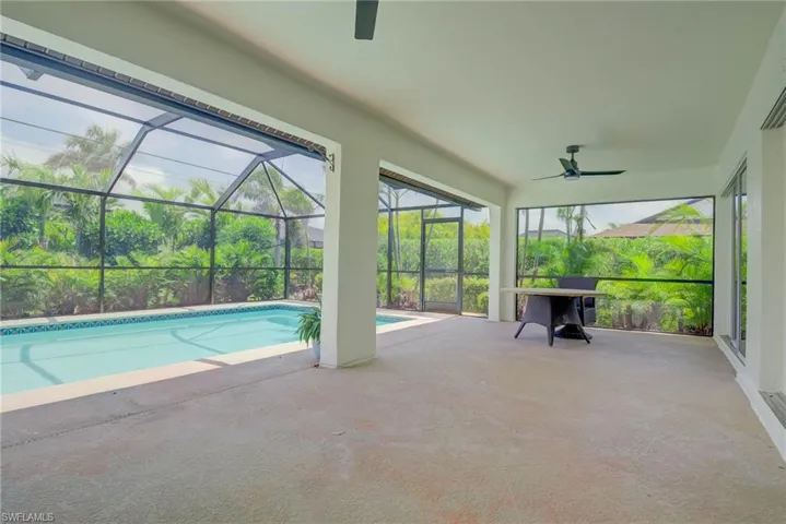 Swimming pool with a ceiling fan, a patio area, and glass enclosure
