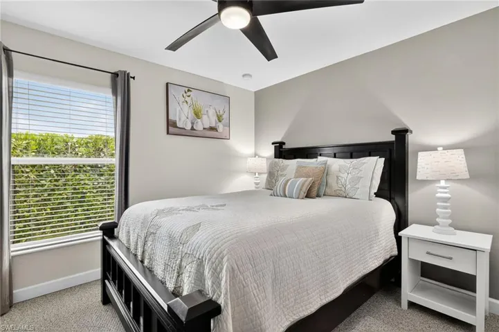 Comfortable bedroom with soft carpet flooring and ceiling fan — perfect as a guest room or home office in this turnkey furnished Cape Coral pool home.