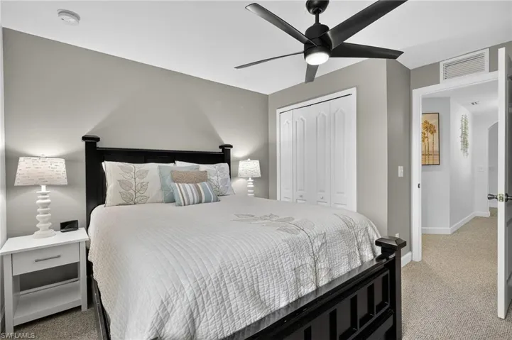 Bedroom with plush light carpet, large closet, and ceiling fan — flexible space ready for guests or personal use at 216 NW 29th Ave, Cape Coral.