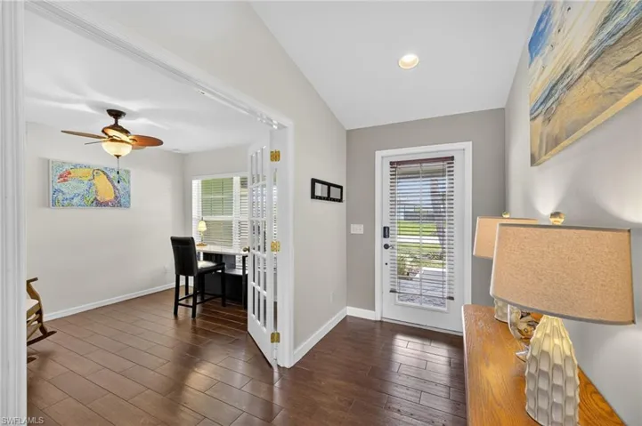 Welcoming foyer entrance with dark wood-style flooring, abundant natural light, ceiling fan, and recessed lighting — sets the tone for this beautifully updated Cape Coral home.