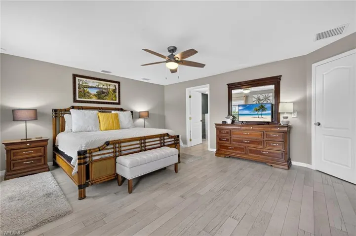 Guest bedroom with light wood-style floors and ceiling fan — bright, airy, and ready to welcome family or vacation renters in this Cape Coral furnished pool home.