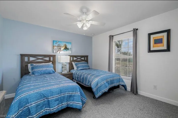 Carpeted bedroom with ceiling fan and clean baseboards — bright and comfortable, ready for immediate occupancy in this Cape Coral furnished home.