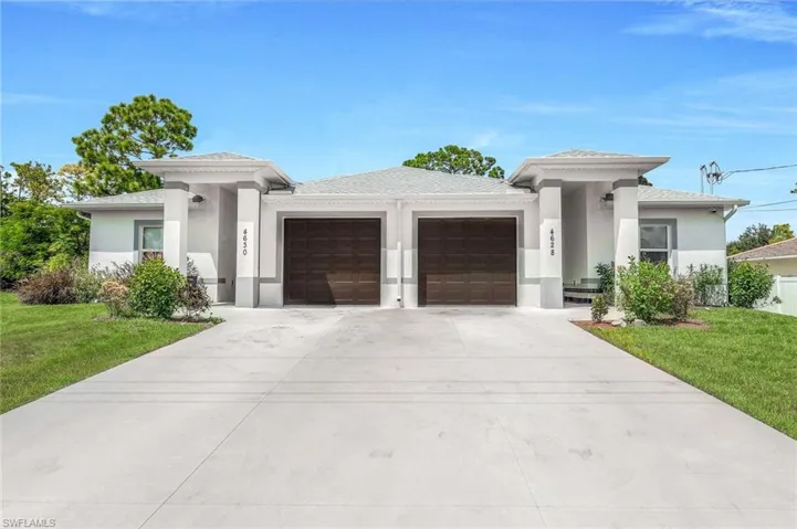 Prairie-style house featuring a front lawn, stucco siding, a garage, and concrete driveway