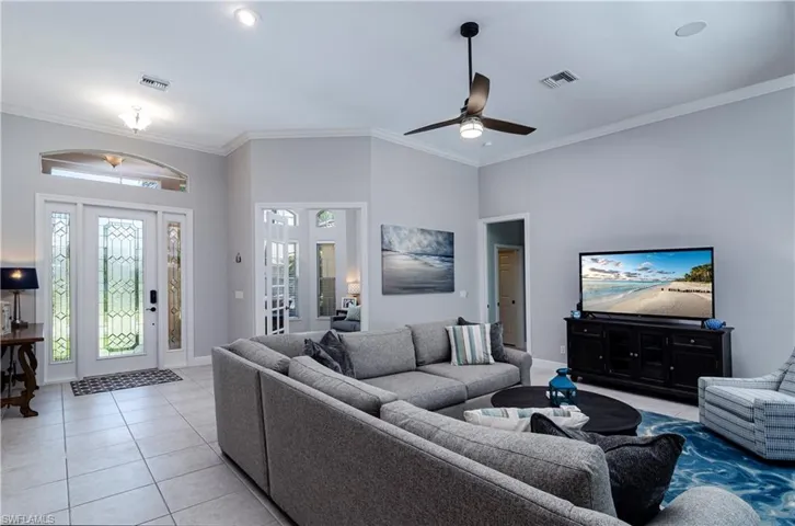 Tiled living room with crown molding and ceiling fan
