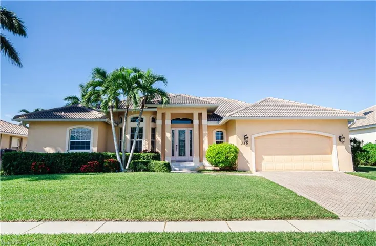 Mediterranean / spanish home featuring a garage, a front lawn, and french doors