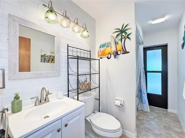 Bathroom with tile walls, toilet, vanity, tile patterned flooring, and tasteful backsplash