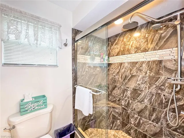 Bathroom featuring toilet and a shower with shower door