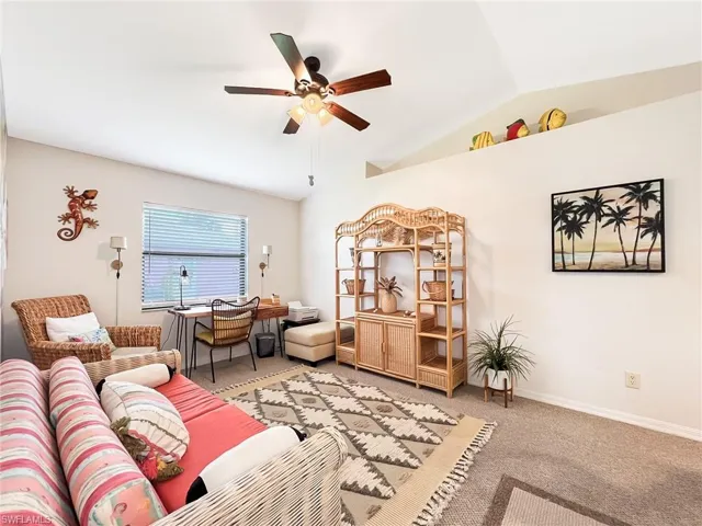 Carpeted living room with ceiling fan and vaulted ceiling
