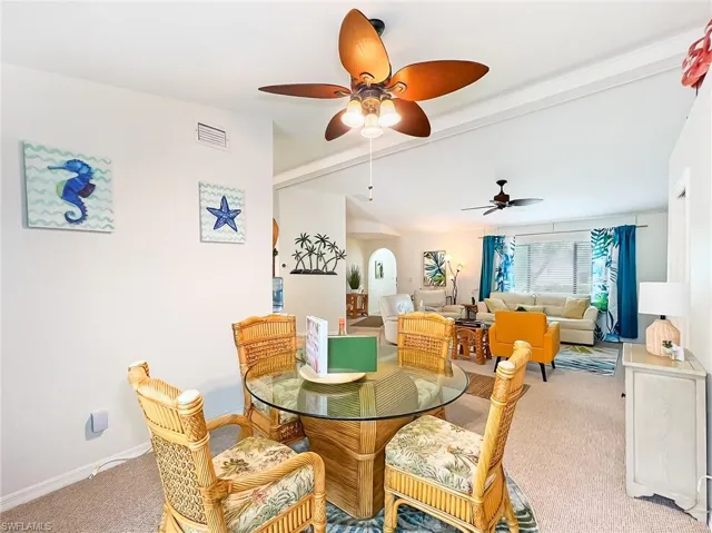 Carpeted dining area with beam ceiling and ceiling fan