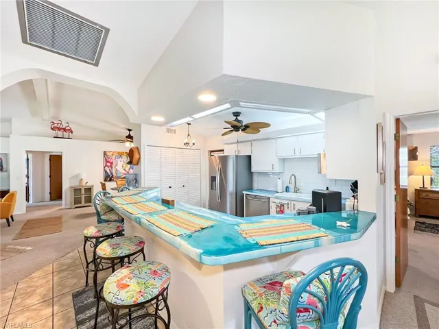 Kitchen with ceiling fan, appliances with stainless steel finishes, and light colored carpet