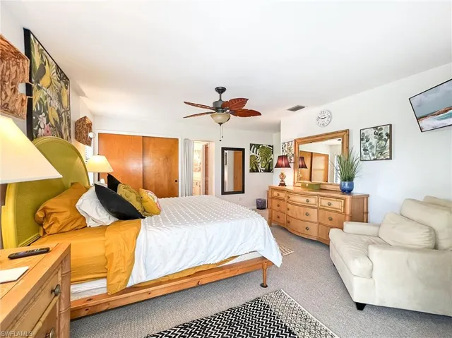 Bedroom with ceiling fan, a closet, and light colored carpet