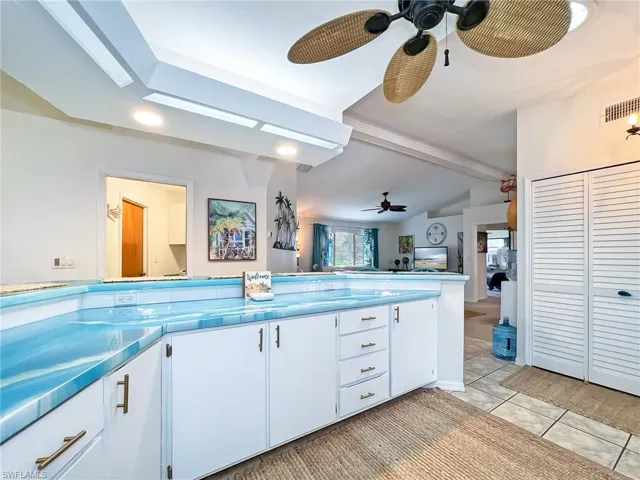 Kitchen featuring ceiling fan, beamed ceiling, light tile patterned floors, and white cabinets