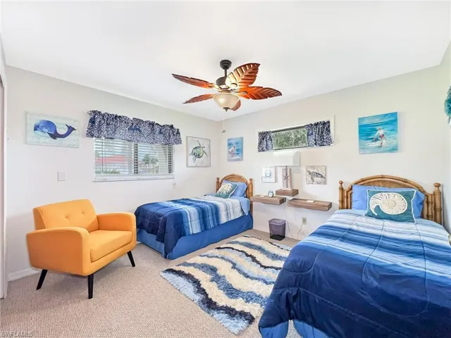Bedroom with ceiling fan, multiple windows, and light colored carpet