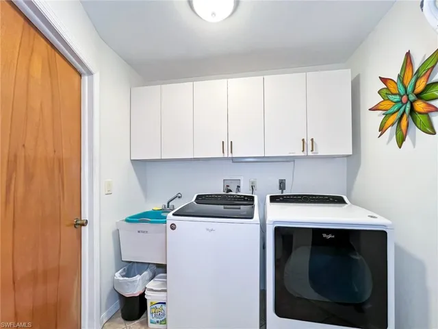 Laundry room featuring light tile patterned floors, cabinets, and separate washer and dryer