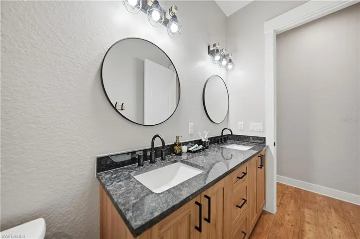 Dual vanity with light wood-finish cabinetry and black hardware