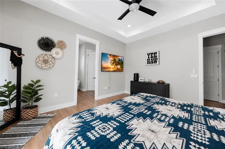 Spacious room featuring wood-finish flooring, a tray ceiling with recessed lighting and a ceiling fan, and light gray wall paint