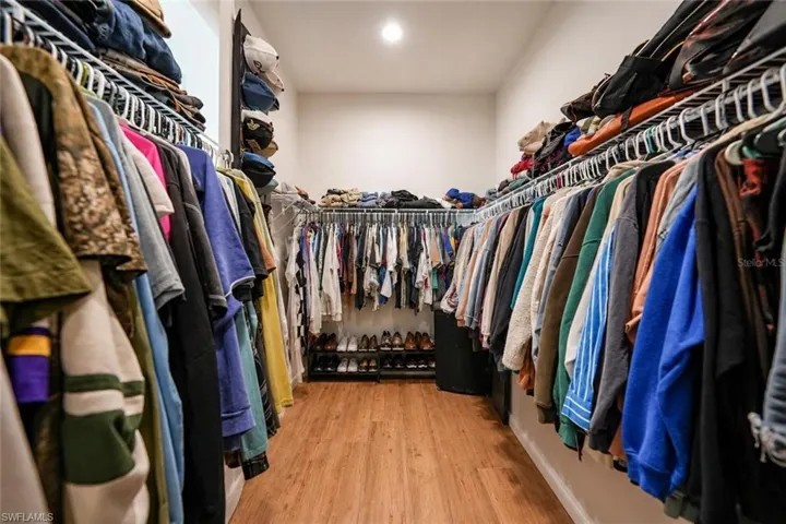 Walk-in closet featuring wood-finish flooring, recessed lighting, and extensive wire shelving with hanging rods
