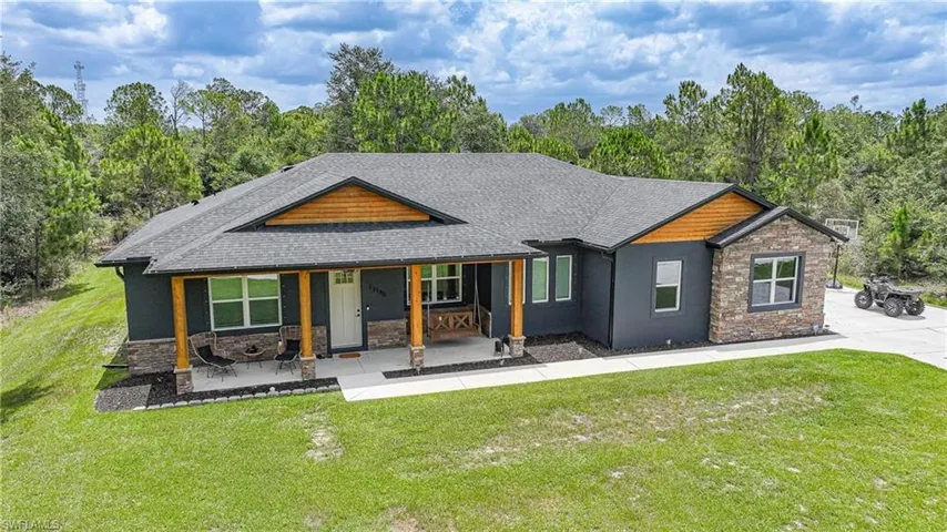 Ranch-style residence featuring a dark gray exterior, stone accents, and a covered front porch with wood-wrapped columns