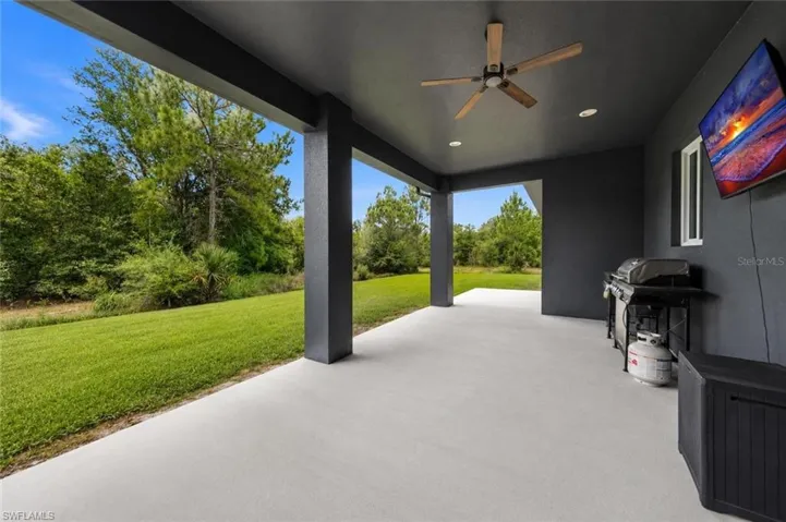 Expansive covered patio featuring a light-colored concrete surface, dark ceiling, and recessed lighting