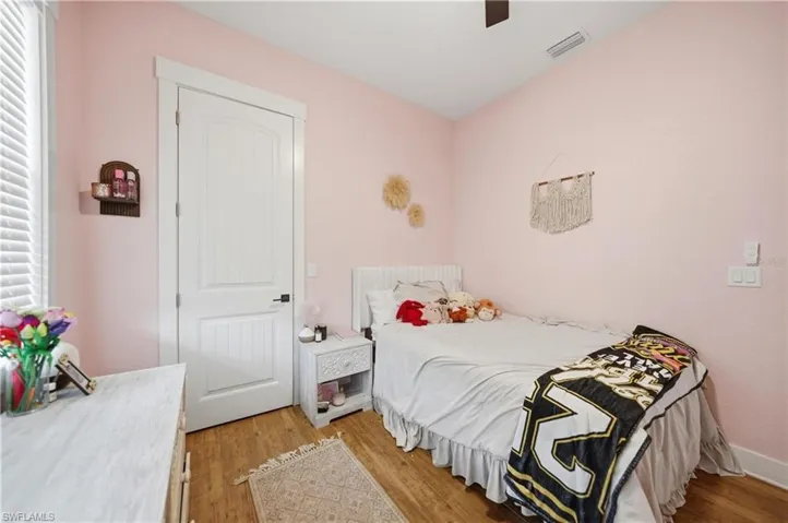 Interior space featuring wood-finish flooring, white trim, and a white paneled door with a dark handle