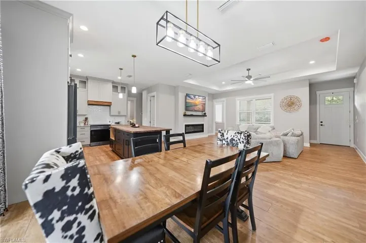 Open-concept living space featuring wood-finish flooring, a modern linear chandelier, and recessed lighting