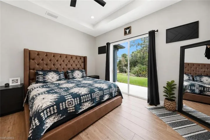 Spacious room featuring wood-finish flooring, a tray ceiling, and a ceiling fan