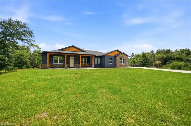 Contemporary single-story residence featuring a dark siding exterior with stone veneer accents