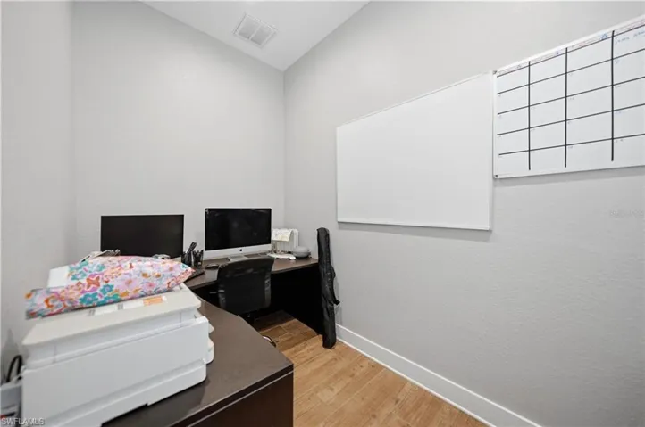 Dedicated office space featuring light gray walls, wood-finish flooring, and white baseboards