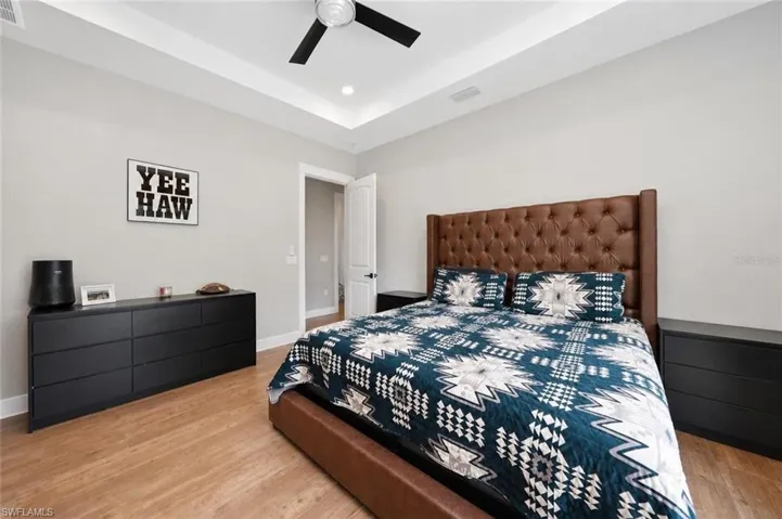 Spacious room featuring wood-finish flooring, a tray ceiling with a ceiling fan, and recessed lighting