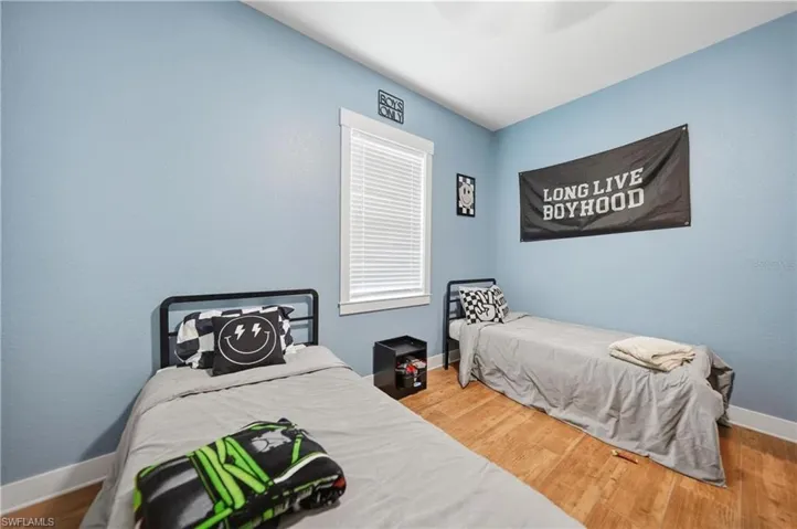 Spacious bedroom featuring light blue walls, wood-finish flooring, and white trim