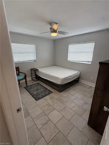 Tile flooring, two windows with blinds, and a ceiling fan with integrated lighting
