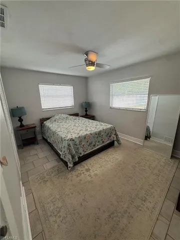 Recessed lighting, ceiling fan with integrated lighting, two windows with blinds, and tiled flooring
