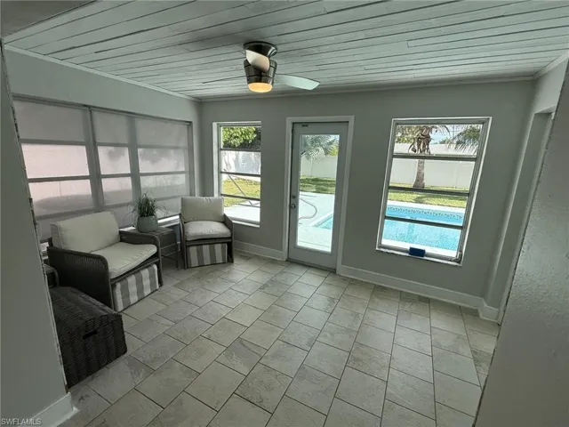 Tiled flooring, paneled ceiling, ceiling fan with integrated lighting, multiple windows, and a glass-paneled door