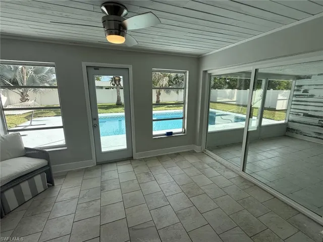 Sunroom with tile flooring, a ceiling fan, and multiple windows
