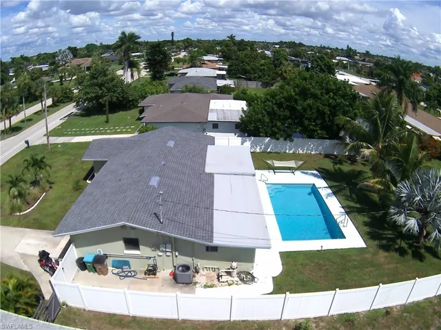 Rectangular swimming pool with white coping, surrounded by a manicured lawn and mature landscaping