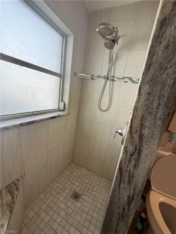 Shower with tiled walls, mosaic accent band, and dual showerheads