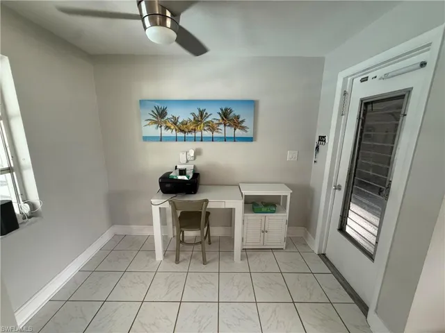 Ceiling fan with integrated lighting, tiled flooring, window with white trim, and a white door with a louvered insert