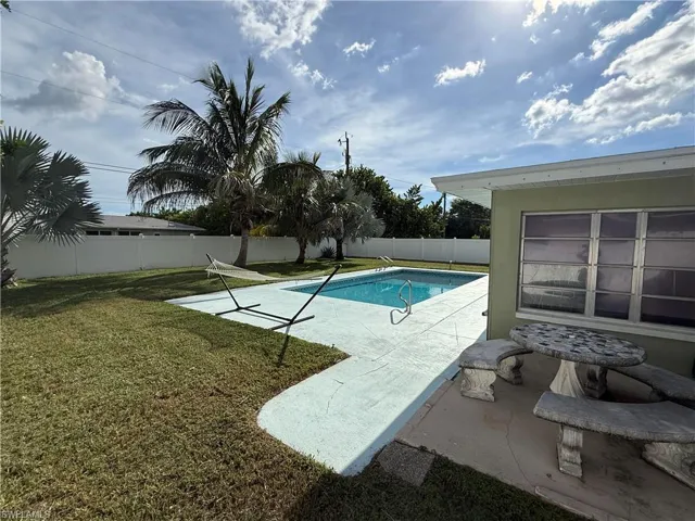 Private backyard featuring a swimming pool, concrete patio, and a privacy fence