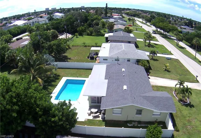 Private fenced backyard with a rectangular swimming pool, concrete patio, and mature trees