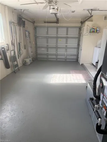 Garage featuring an automatic overhead door, ceiling fan, and painted floor