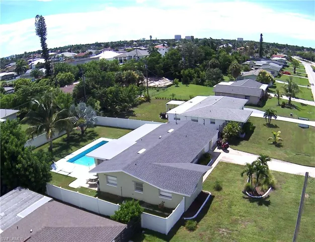 Property featuring an in-ground swimming pool, white privacy fencing, a manicured lawn, and mature palm trees