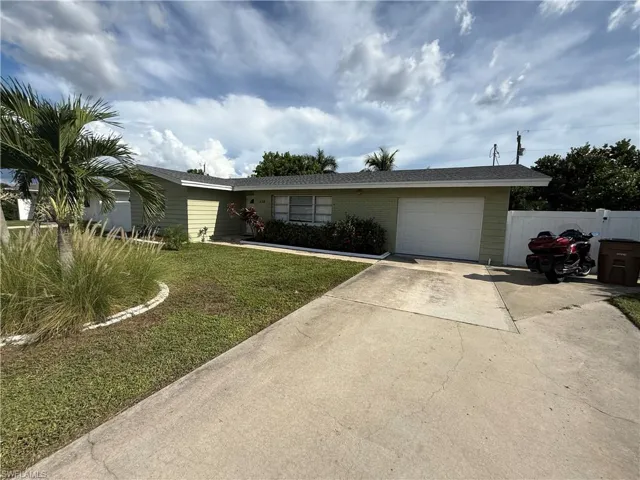Light green exterior with a white garage door, concrete driveway, and a dark shingle roof