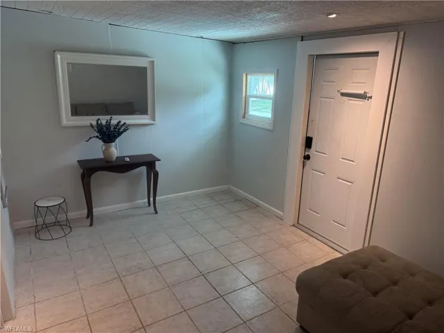Tile flooring, recessed lighting, paneled door, and a single-pane window