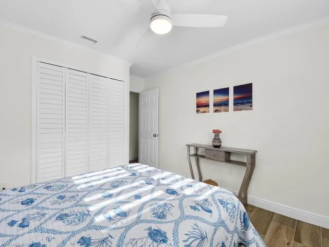 Bedroom featuring crown molding, wood finished floors, a closet, and ceiling fan