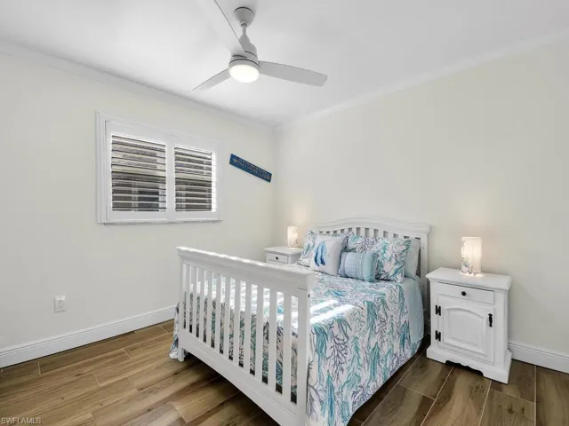 Bedroom featuring wood finish floors, crown molding, and a ceiling fan