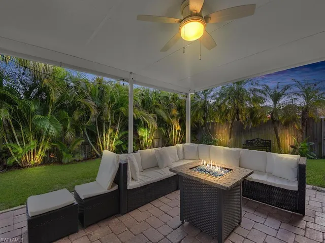 Fenced backyard featuring a ceiling fan, an outdoor living space with a fire pit, and a patio area